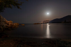Paesaggio notturno con luna piena riflessa sull'acqua del mare, atmosfera suggestiva
