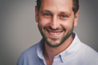 Ritratto ravvicinato di uomo adulto sorridente, luce naturale, sfondo sfocato
