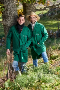 Coppia di uomini in posa all'aperto con tute da lavoro verdi, ambiente naturale