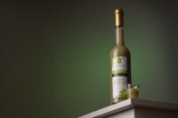 Bottiglia di liquore artigianale con etichetta su sfondo verde scuro, fotografia di prodotto enogastronomico
