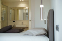 Camera da letto minimalista con comodino, lampada a parete e finestra luminosa