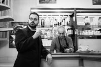 Foto in bianco e nero di un musicista con occhiali, stile reportage
