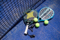 Racchetta da padel con palline gialle su superficie di campo da gioco blu