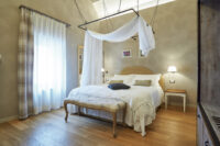 Camera da letto elegante con letto a baldacchino, tende bianche e pavimento in legno