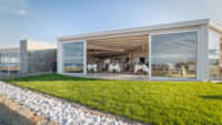 Sala ristorante moderna con grandi vetrate, giardino con pietre decorative e prato verde
