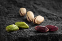 Pistacchi sgusciati e con guscio su pietra lavica scura, fotografia food per prodotti siciliani