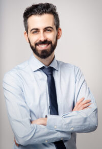 Ritratto di uomo adulto sorridente con barba, sfondo neutro chiaro